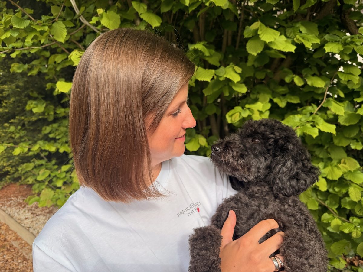 Sarah im weißen Familienhund-mit-Herz-Shirt mit Amy auf dem Arm